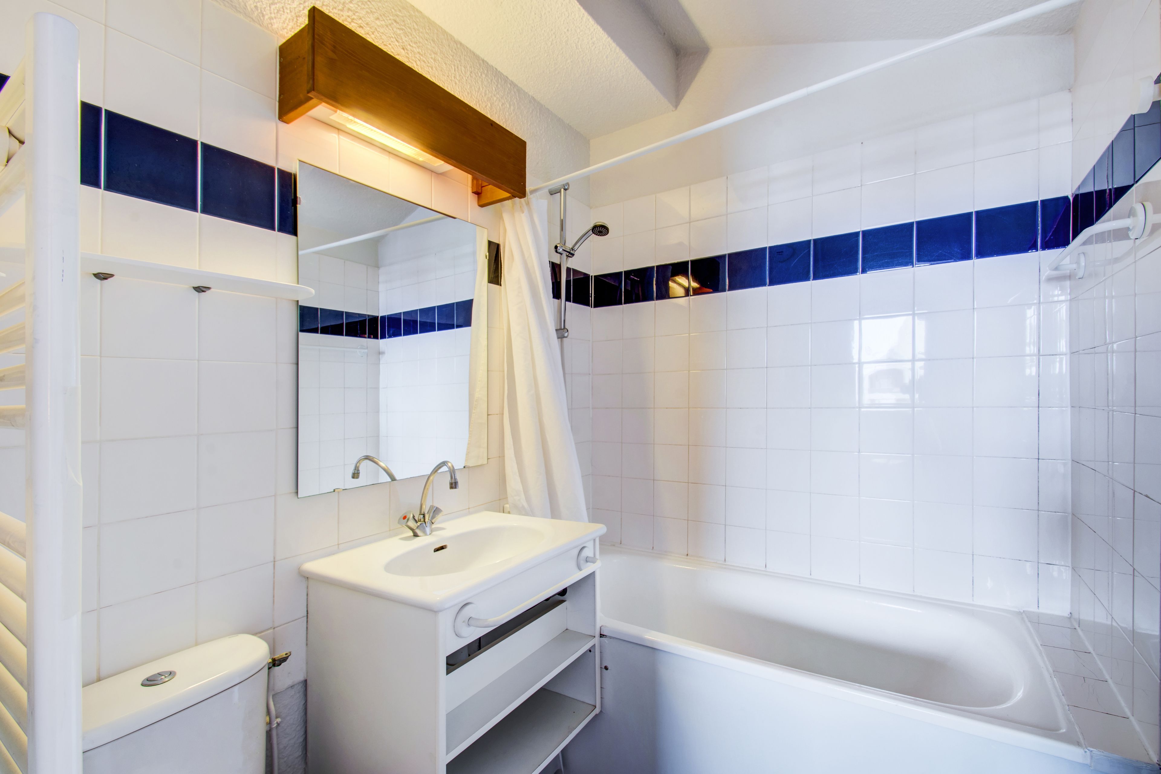 A modern bathroom with a white sink, mirror, and bathtub.
