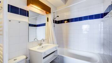 A modern bathroom with a white sink, mirror, and bathtub.