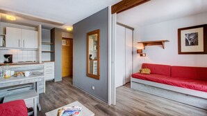 A compact living space with a kitchenette, a dining area, and a red sofa. - Vacancéole - Le Borsat IV (Tignes)