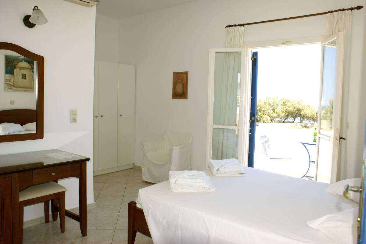 Une chambre d’hôtel avec un lit, un bureau, une chaise et une fenêtre avec des rideaux.