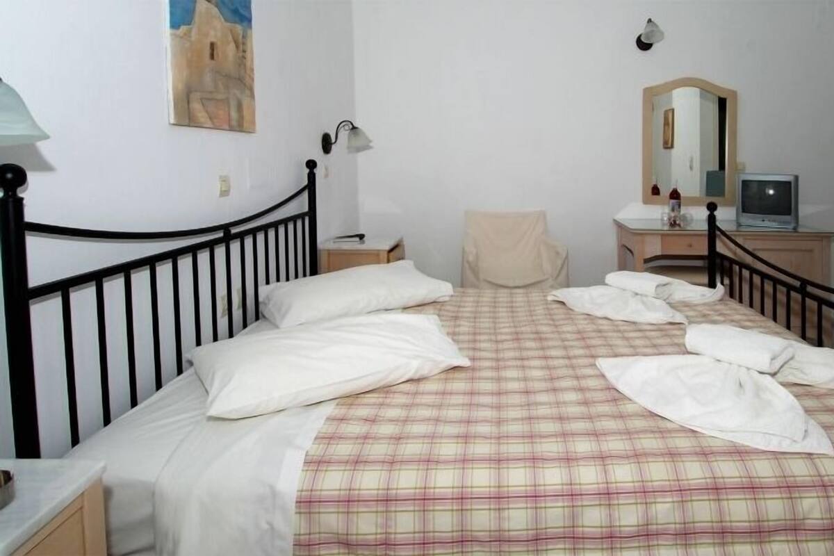 Une chambre à coucher comprenant un lit, une chaise, un bureau, une télévision et un miroir.