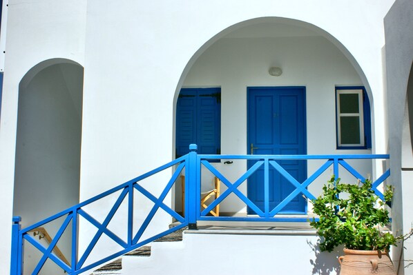 A white building with blue doors and a blue railing. - Hotel Blue Bay Villas (Santorini)