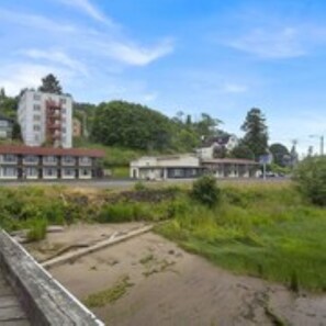 A building with multiple floors and a flat roof, surrounded by greenery and other structures.
