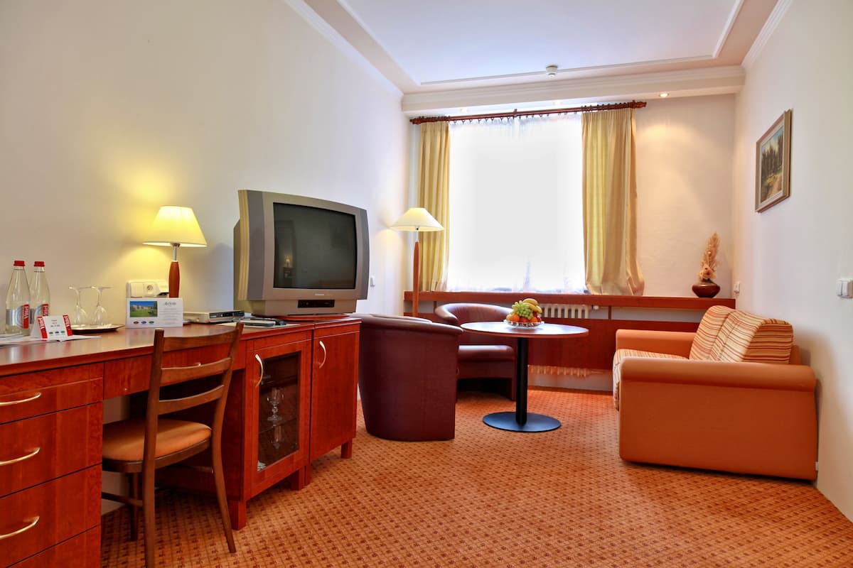 A hotel room with a wooden desk, television, and a sofa.