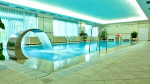 An indoor swimming pool with a modern design, including a unique water feature and seating areas. - Top Hotel Agricola (Marianske Lazne)