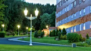 A well-maintained hotel entrance with a landscaped garden, a street lamp, and a building with multiple windows. - Top Hotel Agricola (Marianske Lazne)