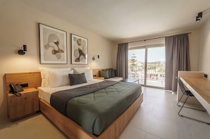Una camera d'albergo moderna con un letto grande, una scrivania, un telefono sul comodino e opere d'arte alle pareti.