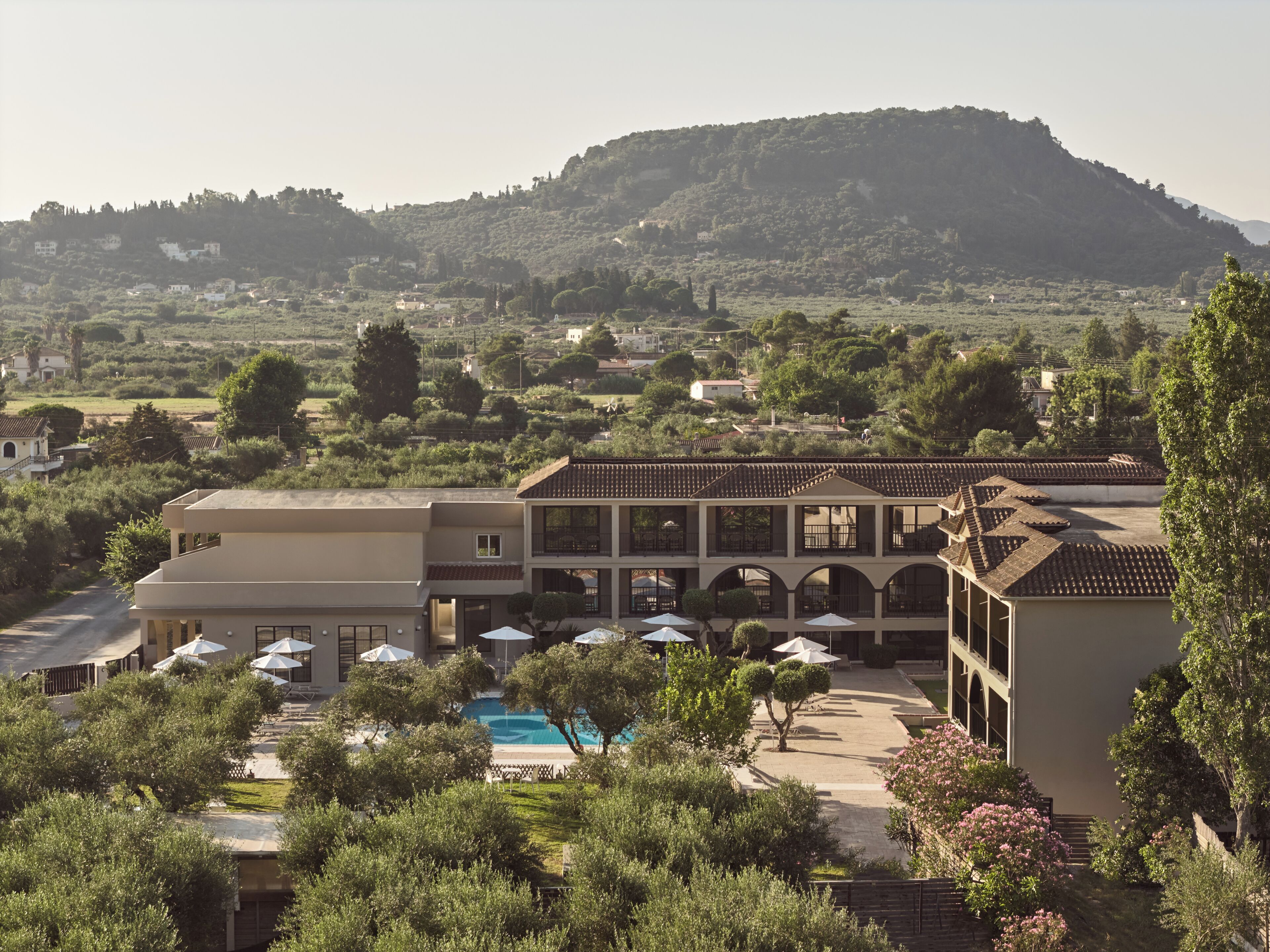 Um hotel com piscina, área de estar ao ar livre e vista para uma colina.