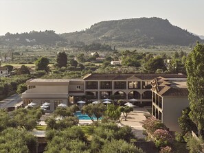 Ein Hotel mit Pool, Sitzgelegenheiten im Freien und Blick auf einen Hügel.