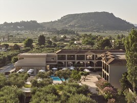Un hotel con piscina, area salotto esterna e vista su una collina.