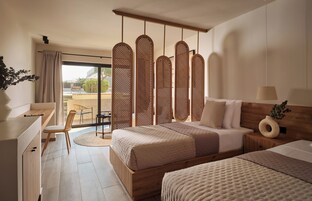 Quarto de hotel moderno com uma cama grande, uma escrivaninha e vista para o exterior.