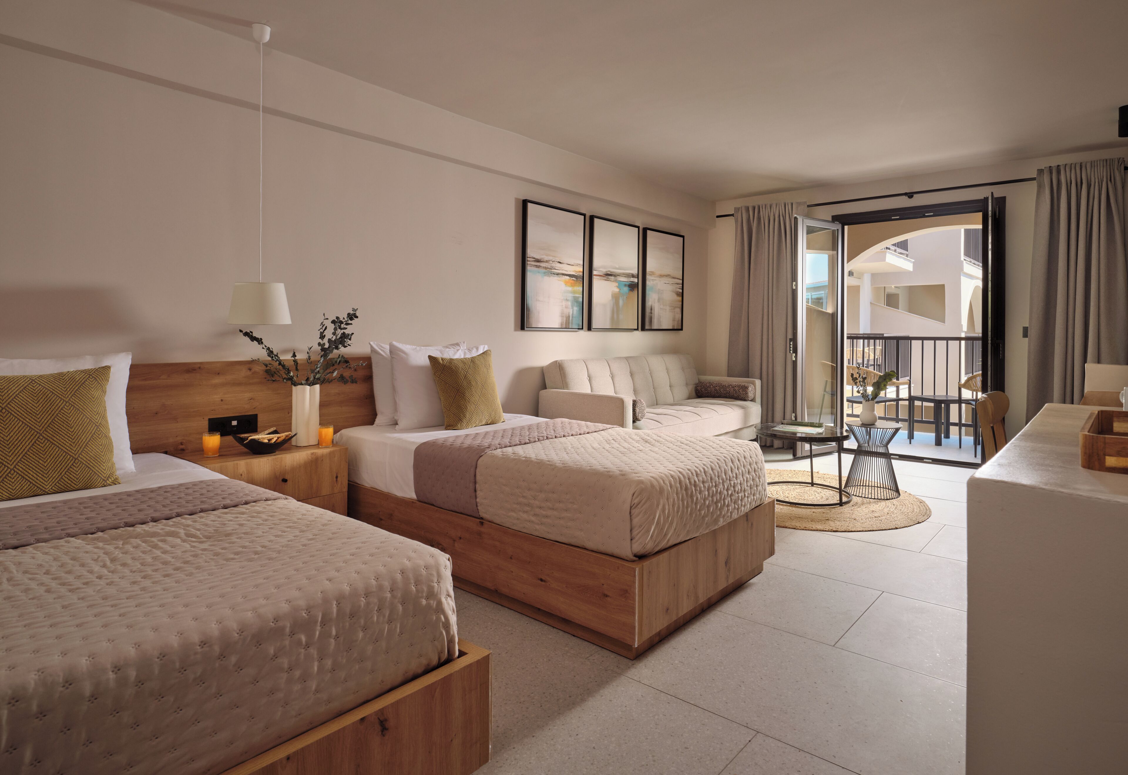 Habitación de hotel con dos camas, una mesita, una silla y un balcón con vistas.