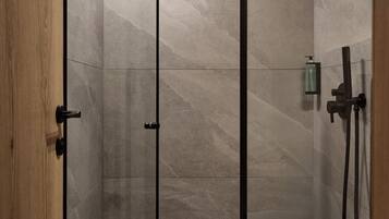 A modern shower with a glass door, a handheld showerhead, and a handheld shower attachment.