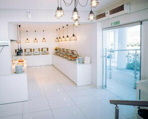 Eine moderne Hotelhalle mit Empfangstresen, Pendelleuchten und einer Glastür, die auf einen Balkon führt.