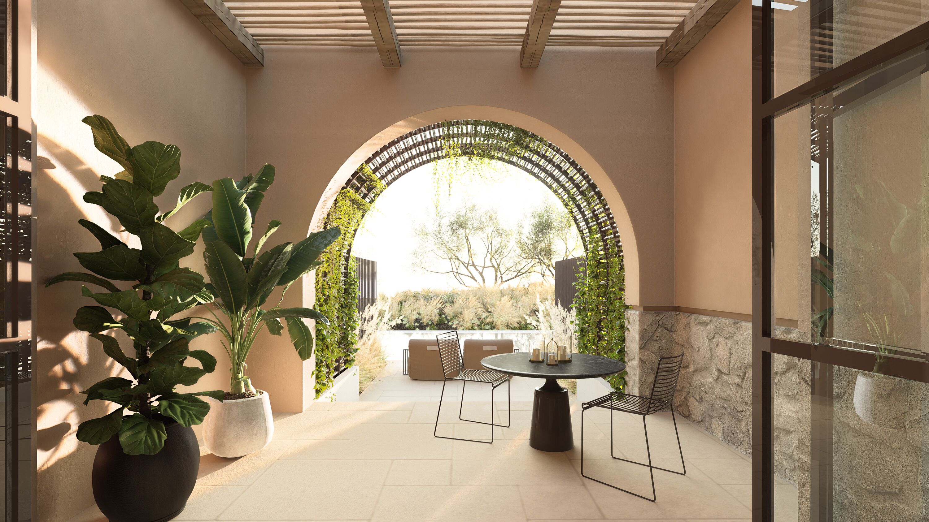 An outdoor patio with a round table and chairs, a large potted plant, and an arched entrance with greenery.