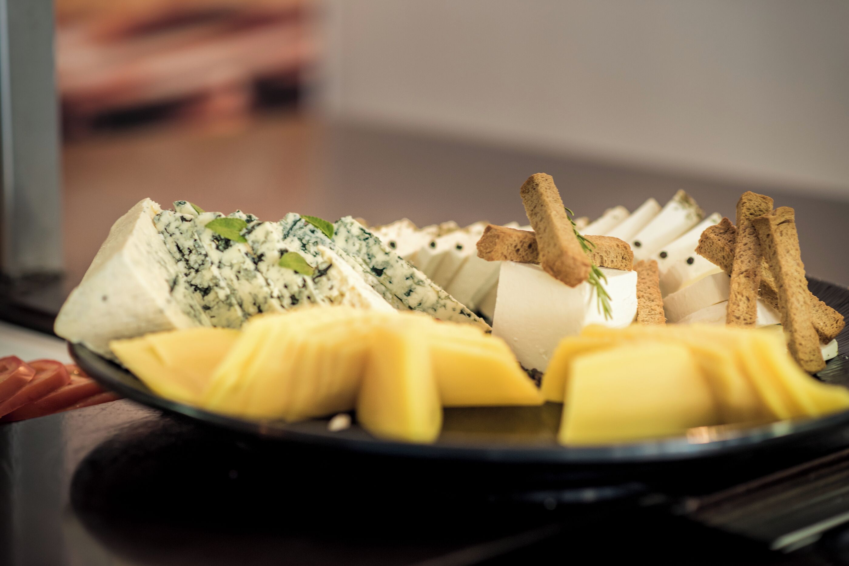 A cheese platter with various cheeses and crackers on a plate.