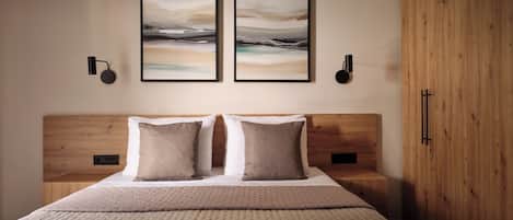 Ein Schlafzimmer mit einem hölzernen Kopfstück, einem Bett mit zwei Kissen und zwei gerahmten abstrakten Bildern an der Wand.