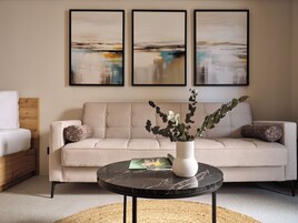 Un soggiorno con un divano, un tavolino con un vaso e tre opere d'arte appese alla parete.