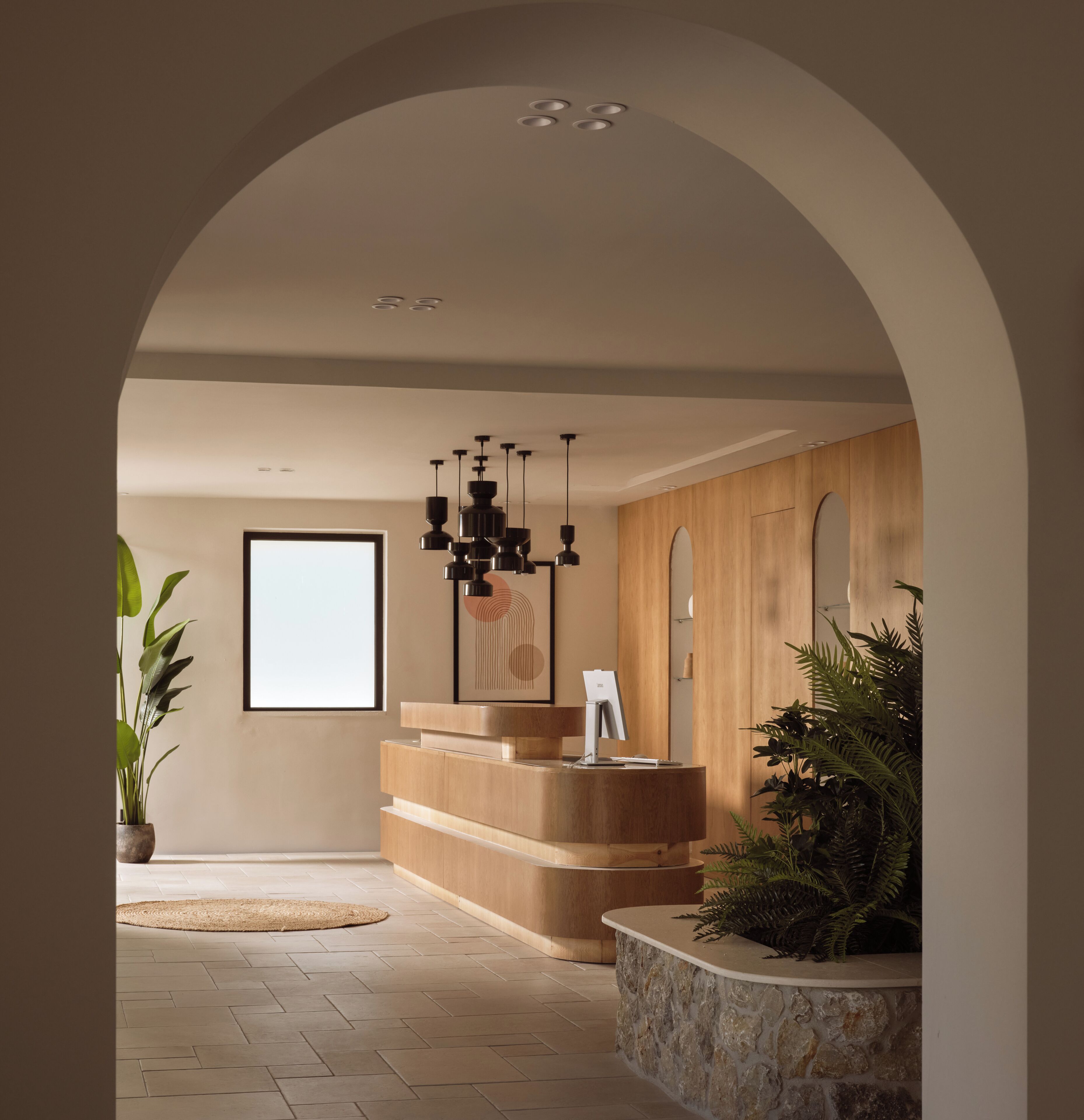 Uma área de recepção com balcão de madeira, um lustre moderno e uma janela grande.