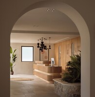 Un'area di accoglienza con una scrivania in legno, un lampadario moderno e un'ampia finestra.