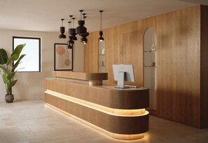 Bancada de recepção com design moderno, revestimento em madeira e iluminação integrada.