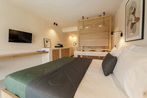 Quarto de hotel moderno com cama, televisão, parede de painéis de madeira e mesa de cabeceira.