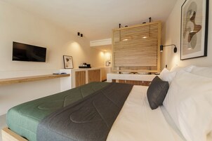 Una camera d'albergo moderna con un letto, una TV, un pannello a parete in legno e un comodino.