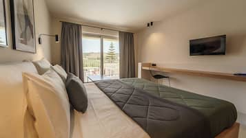 Ein Hotelzimmer mit zwei Betten, einem Fernseher, einem Schreibtisch und Blick ins Freie.