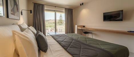 Habitación de hotel con dos camas, televisión, escritorio y vistas al exterior.