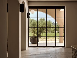 A room with a large sliding glass door leading to an outdoor area with a potted plant and trees. - Filoxenia Hotel Zakynthos (Zakynthos)