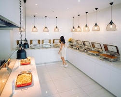 Un'area buffet con diverse postazioni di cibo, un addetto al servizio e illuminazione a sospensione.
