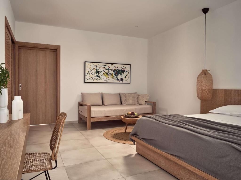Quarto moderno com cama, sofá, escrivaninha e cadeira.