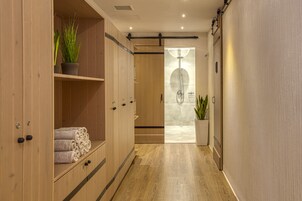 Un pasillo con taquillas de madera, zona de duchas y plantas en macetas.