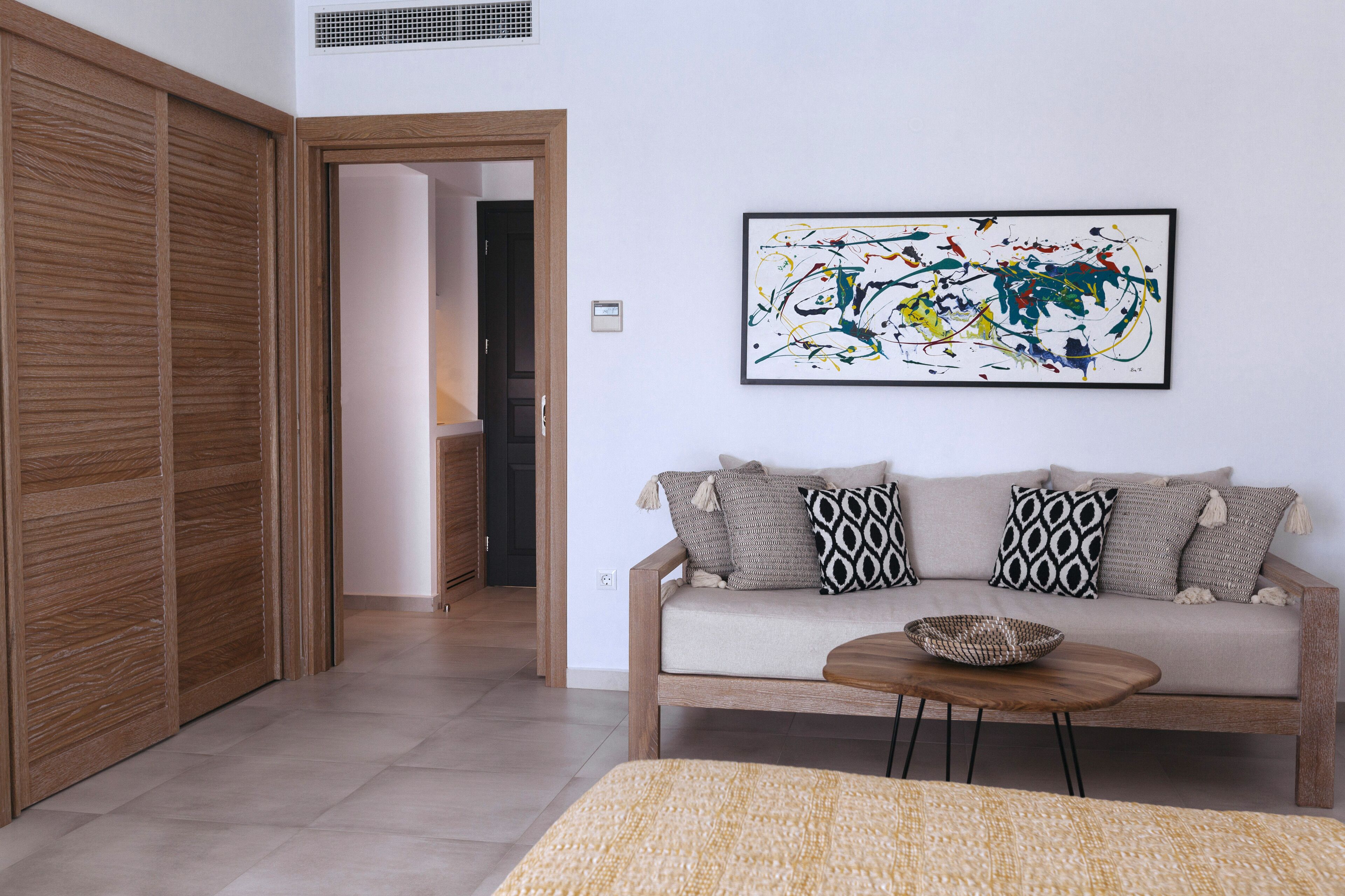 Una sala de estar con un sofá, una mesa de centro y un cuadro abstracto grande en la pared.