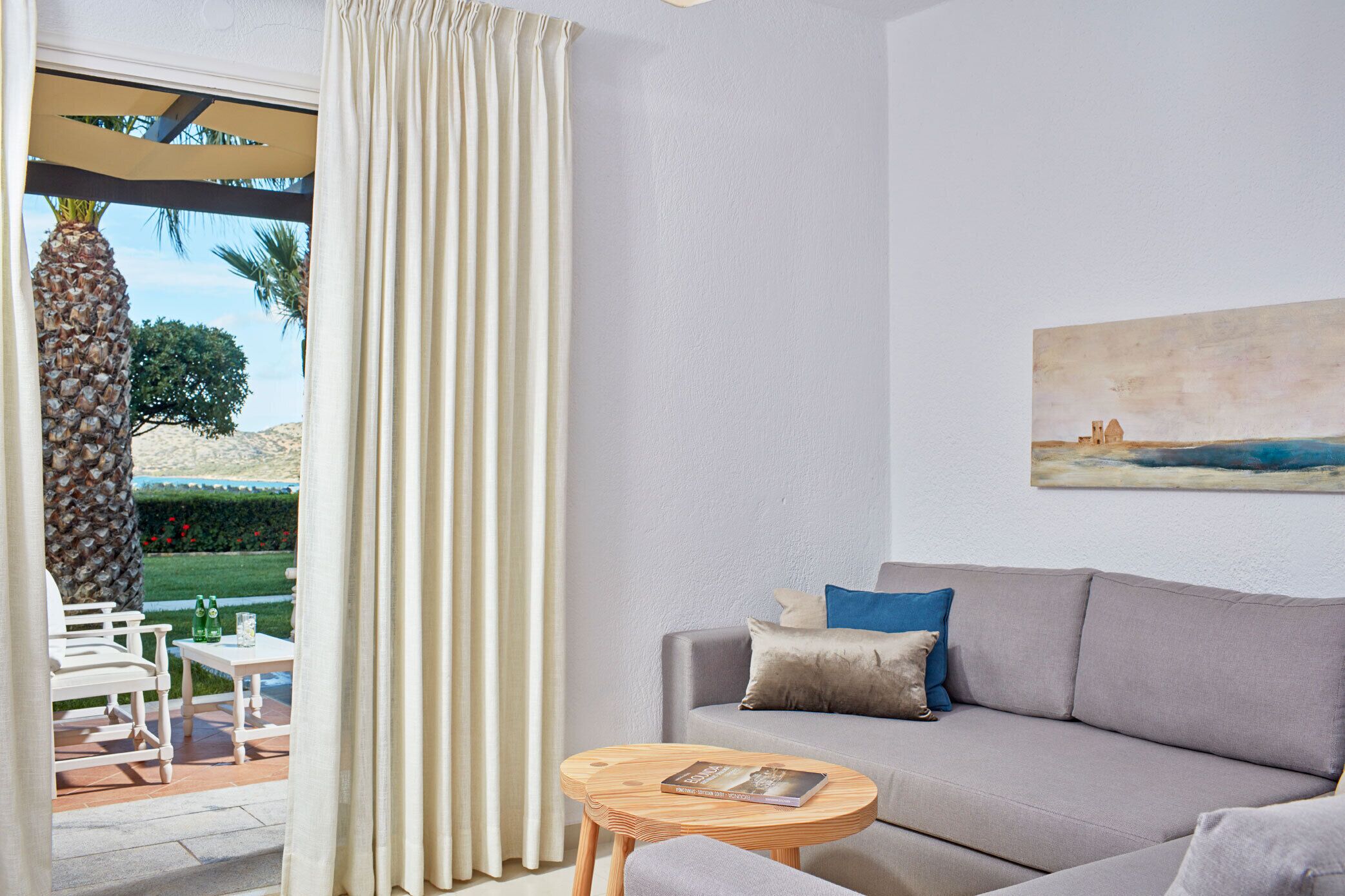 A living room with a sofa, a small table, and a view of the outdoors.