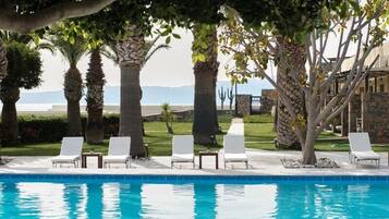 A pool area with lounge chairs and palm trees.