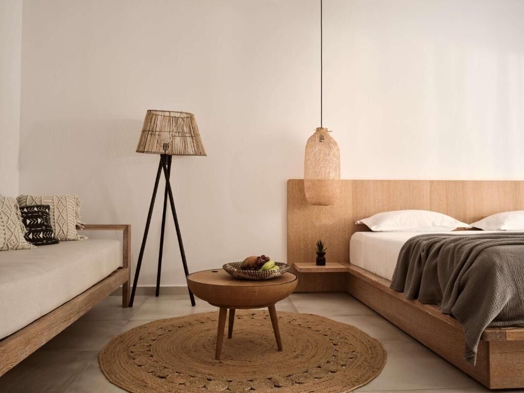 Ett minimalistiskt sovrum med en säng, ett sängbord, en lampa och en hängande taklampa.