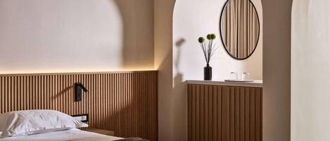 Een moderne hotelkamer met een houten hoofdbord, nachtkastje, spiegel en een kleine plant.