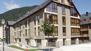 Ein mehrstöckiges Gebäude mit großen Fenstern, einer Steinaußenfassade und einem Balkon.