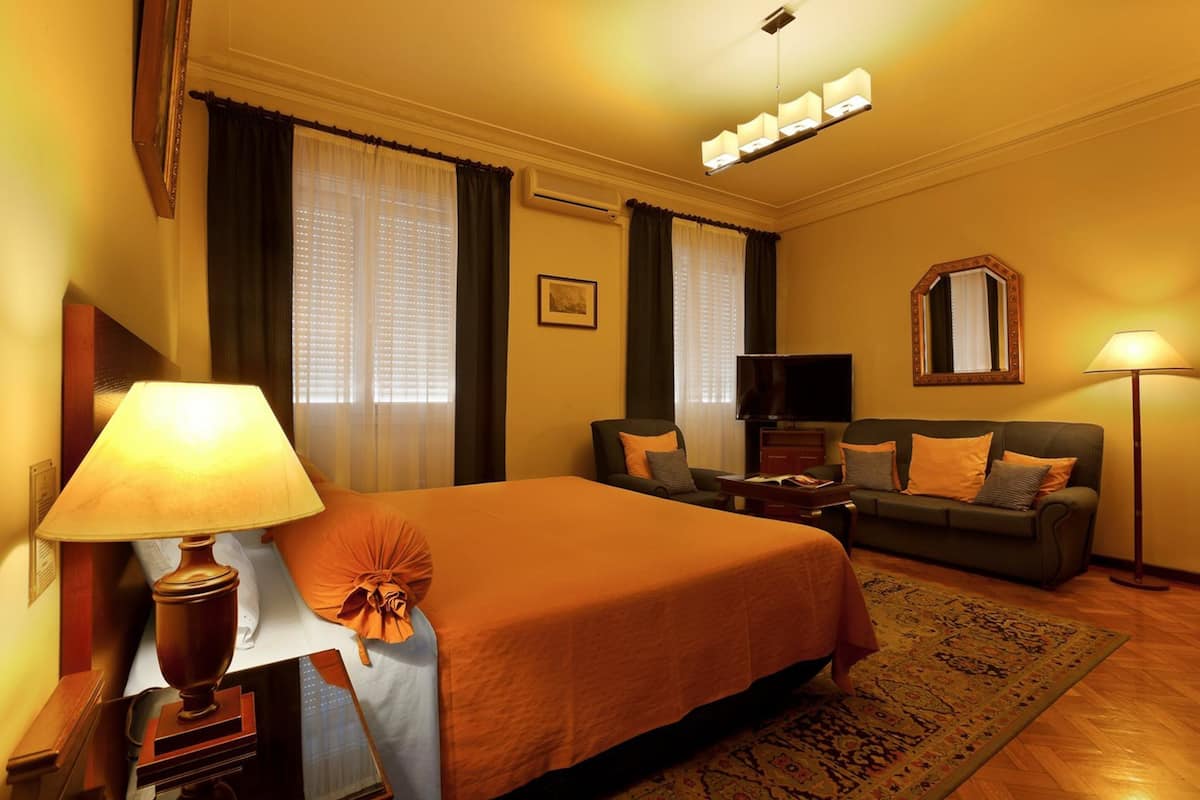 A hotel room with a large bed, a sofa, a TV, and a desk.