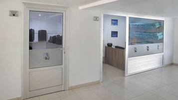 Ein Hotelzimmer mit Gepäckablage, einer Minibar und Blick auf die Stadtlandschaft durch eine Glastür.