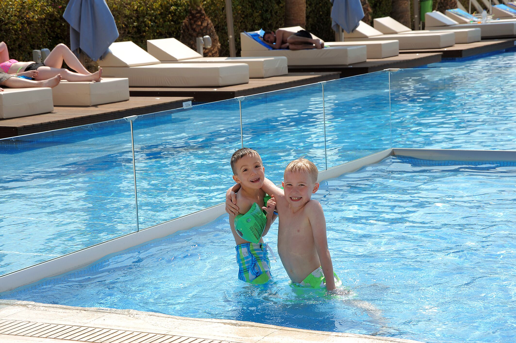 A swimming pool with lounge chairs and a tiled deck.