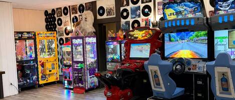 Una habitación con mesa de fútbol, juegos de arcade y una pared decorada con discos de vinilo.