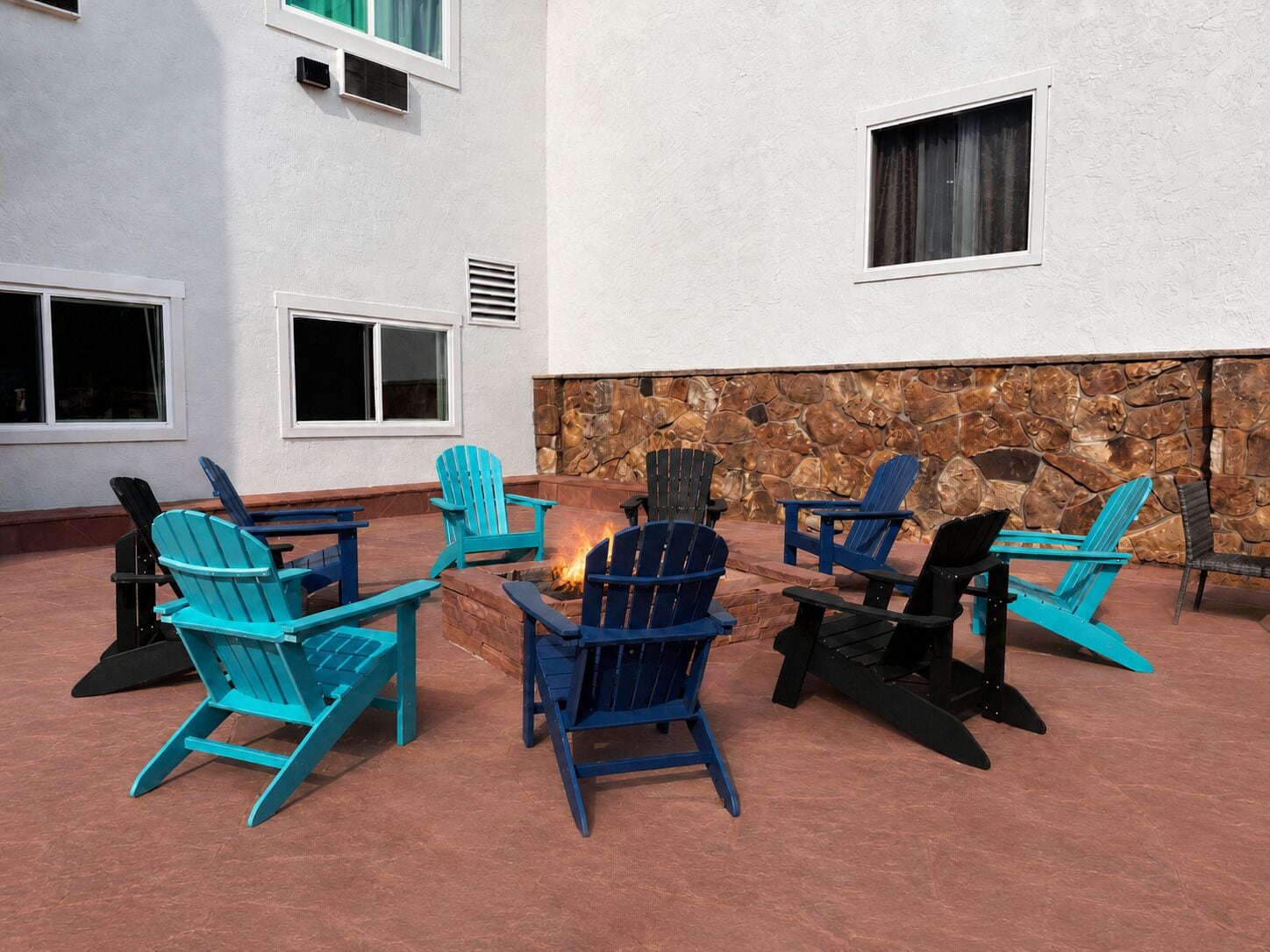 An outdoor seating area with Adirondack chairs and a fire pit.