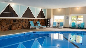 A swimming pool with lounge chairs, a stone wall, and a view of the outdoors. - Expedition Lodge Estes Park (Estes Park)