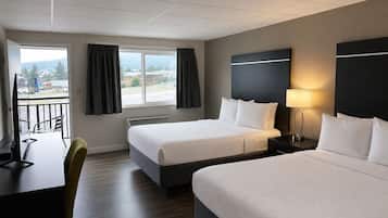 Habitación de hotel con dos camas, un escritorio, una silla, un televisor y una ventana con cortinas.