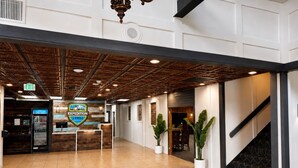 A hotel lobby with a reception desk, a vending machine, potted plants, and a staircase. - Expedition Lodge Estes Park (Estes Park)