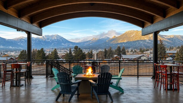 A covered outdoor seating area with a fire feature, chairs, and a view of mountains. - Expedition Lodge Estes Park (Estes Park)