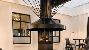 A modern interior with a central fireplace, seating area, and a book on a table. - Expedition Lodge Estes Park (Estes Park)