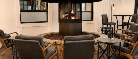 A modern interior with a central fireplace, seating area, and a book on a table.